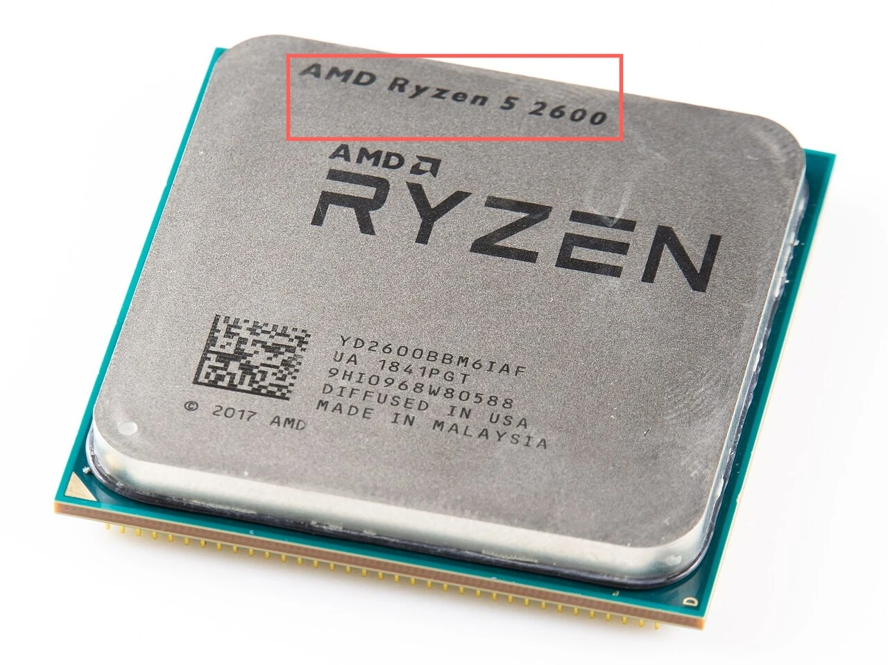 A desktop CPU seen from above: a grey metal lid printed with a large logo and, along its top edge, the text AMD Ryzen 5 2600, over a green circuit-board base with gold pins along the lower edge. A red box surrounds the model name